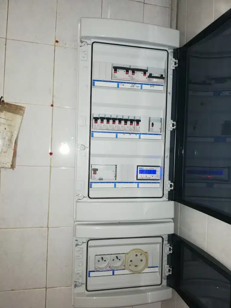 Tableau Électrique avec Disjoncteurs Legrand et Compteur Tableau électrique Legrand avec disjoncteurs, compteur digital et prises de courant sur carrelage blanc.